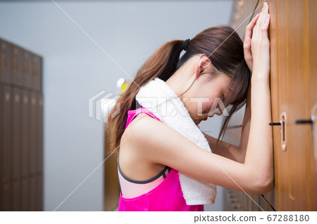 Young woman worried at locker in gym Young woman worried at locker in gym 67288180