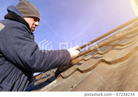 Installation by the master on a roof of the house of snow stops. Installation on metal of brackets for detention and crushing of ice and snow. 67288238