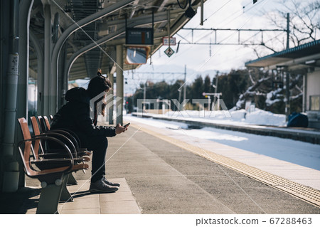 woman using phone waiting for train at station woman using phone waiting for train at station 67288463