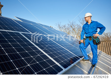 Electrician mounting solar panel on roof of modern house Electrician mounting solar panel on roof of modern house 67292419