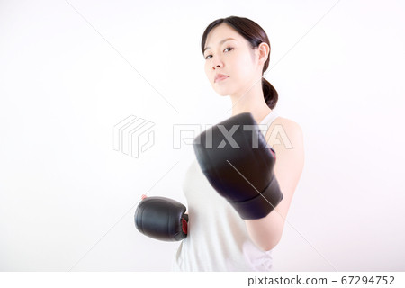 Woman exercising with boxing gloves indoors Woman exercising with boxing gloves indoors 67294752