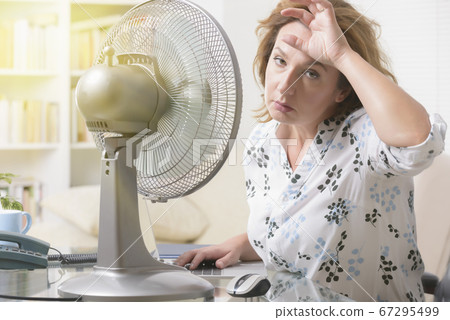 Woman suffers from heat in the office or at home Woman suffers from heat in the office or at home 67295499