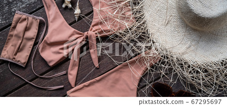Summer holiday vacation and new normal concept, top view of stylish pink or beige bikini swimsuit and women's accessories with protective medical face mask Summer holiday vacation and new normal concept, top view of stylish pink or beige bikini swimsuit and women's accessories with protective medical face mask 67295697