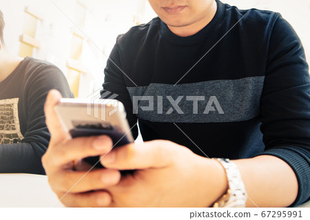 New messages on smartphone, man  looking at mobile phone checking email or message 67295991
