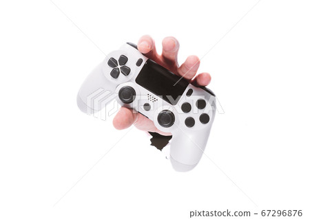 male hand with a gamepad through a hole in paper on isolate white background. close copy space male hand with a gamepad through a hole in paper on isolate white background. close copy space 67296876