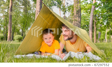 Father and son in tent. The child spends time with his father outdoors. The boy laughs at adult jokes. Travel close to home. Father and son in tent. The child spends time with his father outdoors. The boy laughs at adult jokes. Travel close to home. 67297552