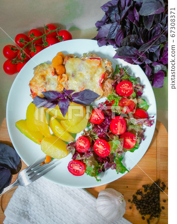 Prepared French style meat dish with potato slices and cherry tomatoes 67308371