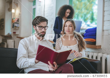 Guy with glasses with book and two girls. Guy with glasses with book and two girls. 67309455