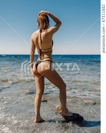 Sexy young woman in bikini posing at stone beach. Attractive model with sporty body Sexy young woman in bikini posing at stone beach. Attractive model with sporty body 67311882