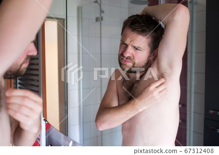 Young man checking his lymph node under armpit being worried about cancer 67312408