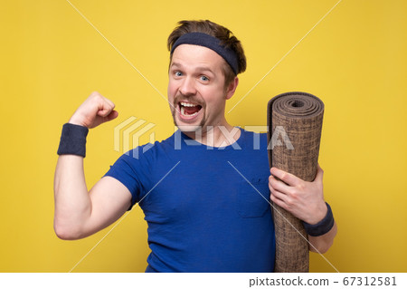 Handsome athletic man at the gym with a mat shjowing his bicep Handsome athletic man at the gym with a mat shjowing his bicep 67312581