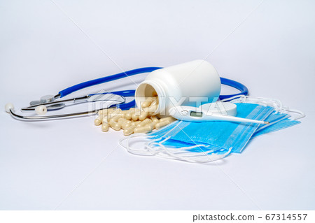 Disposable Medical protective mask with can of pills and thermometer over light grey background 67314557