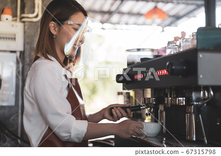 Close up image of barista wearing face shield preparing coffee at cafe Close up image of barista wearing face shield preparing coffee at cafe 67315798