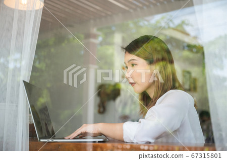 Asian woman working on laptop in coffee shop Asian woman working on laptop in coffee shop 67315801