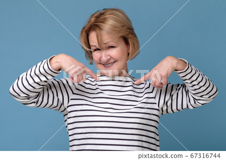 Happy mature woman pointing fingers at herself. Select me please concept. 67316744