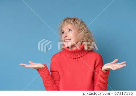 Doubtful mature woman shrugs shoulders having no idea what to do Doubtful mature woman shrugs shoulders having no idea what to do 67317150