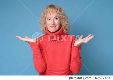 Doubtful mature woman shrugs shoulders having no idea what to do Doubtful mature woman shrugs shoulders having no idea what to do 67317154