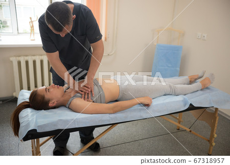 Young woman having osteopathic treatment - the doctor pushing on her chest Young woman having osteopathic treatment - the doctor pushing on her chest 67318957