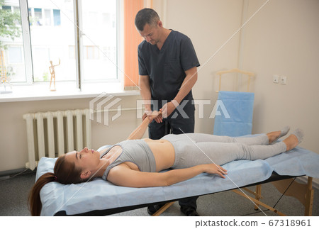 Young woman having osteopathy treatment indoors - doctor massaging her hands and fingers Young woman having osteopathy treatment indoors - doctor massaging her hands and fingers 67318961
