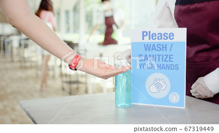 Asian restaurant waitress use hand sanitizer, alcohol gel washer on customer's hand. New normal life Asian restaurant waitress use hand sanitizer, alcohol gel washer on customer's hand. New normal life 67319449