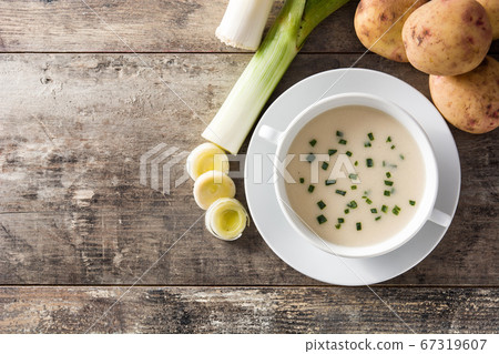 French vichyssoise soup in bowl on wooden table. Top view. Copy space French vichyssoise soup in bowl on wooden table. Top view. Copy space 67319607