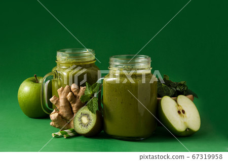 Healthy green smoothie in jar on green background Healthy green smoothie in jar on green background 67319958