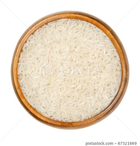 White Basmati rice in wooden bowl. Rice variety with long, slender grains and aromatic smell and taste, traditionally from Indian subcontinent. Closeup from above over white isolated macro food photo. 67321669