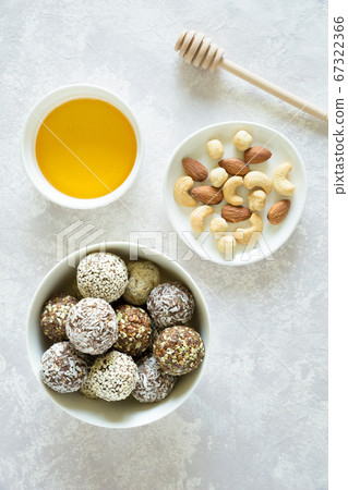 Healthy vegetarian balls with cashews, hazelnuts, peanut butter and almond in the white bowl on the gray background. Vegetarian, organic food. Flat lay, close up. Healthy vegetarian balls with cashews, hazelnuts, peanut butter and almond in the white bowl on the gray background. Vegetarian, organic food. Flat lay, close up. 67322366