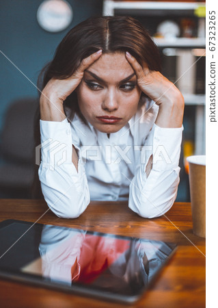 Exhausted business woman sits at workplace taking head in hands. Tired or bored female employee feels stress. Disappointment concept. Tinted image Exhausted business woman sits at workplace taking head in hands. Tired or bored female employee feels stress. Disappointment concept. Tinted image 67323265
