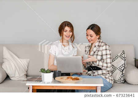 One-on-one meeting.Two young business women sit at a Desk in the office. The girl shows her colleague information on the laptop screen. Women discuss their work online and blog.  67323641