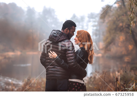 Interracial couple posing in autumn leaves 67325958