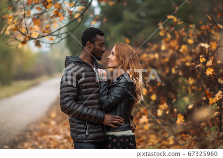 Happy Interracial couple posing in blurry autumn 67325960