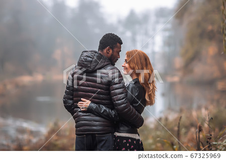 Interracial couple posing in autumn leaves 67325969