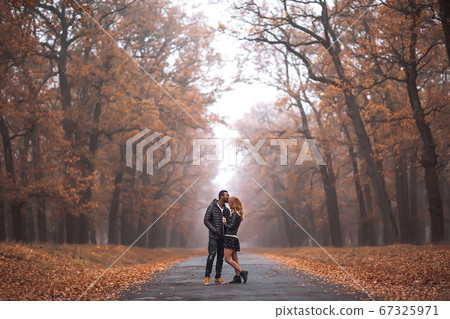 Interracial couple posing in autumn park road 67325971