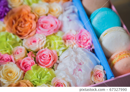 Close up top view - colorful macaroons and flowers in gift box on table at shop Close up top view - colorful macaroons and flowers in gift box on table at shop 67327990