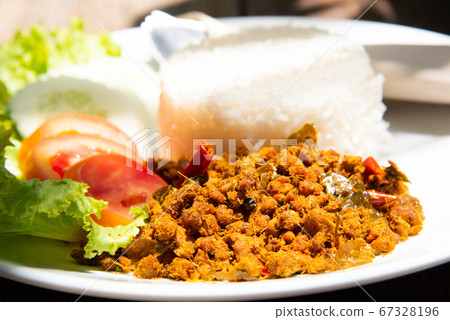 yellow curry mince prok stir fry with rice and tomato cucamber salad with another food on white plate and wood table stock photo 67328196