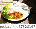 yellow curry mince prok stir fry with rice and tomato cucamber salad with another food on white plate and wood table stock photo 67328197