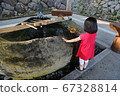 Girl in red clothes purifying hands at the shrine's waterhouse 67328814