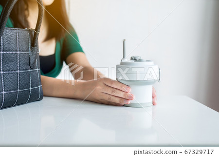 Blured woman showing thumb up with reusable coffee mug,Healthy green,Zero waste,Environmental friendly,Conscious lifestyle concept Blured woman showing thumb up with reusable coffee mug,Healthy green,Zero waste,Environmental friendly,Conscious lifestyle concept 67329717