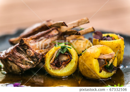 Roasted lamb ribs with stuffed potato on black 67332506
