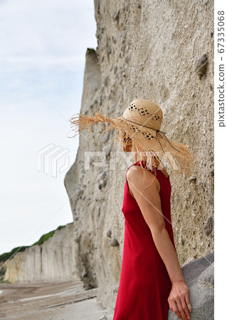 Shot a woman in a straw hat in a red cami dress on the sandy beach of Takise coast, Otobe town, Hokkaido Shot a woman in a straw hat in a red cami dress on the sandy beach of Takise coast, Otobe town, Hokkaido 67335068