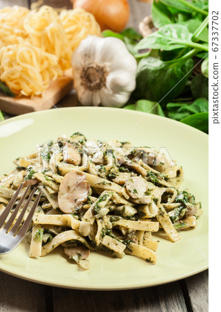 Tagliatelle pasta with spinach and mushrooms on a Tagliatelle pasta with spinach and mushrooms on a 67337702