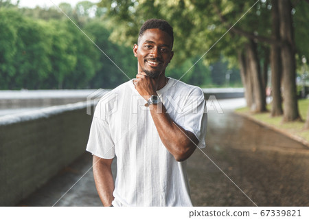 Young man smiling at camera in a park. Horizontally framed shot. 67339821