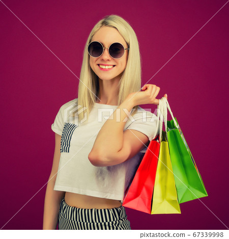 Happy girl in sunglasses holds shopping bags Happy girl in sunglasses holds shopping bags 67339998