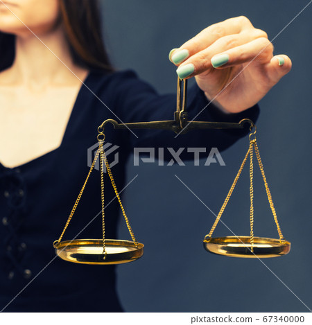 Serious woman holding the justice scale on dark Serious woman holding the justice scale on dark 67340000