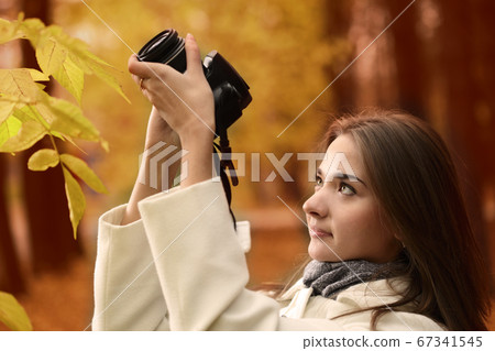 girl with camera in autumn forest 67341545