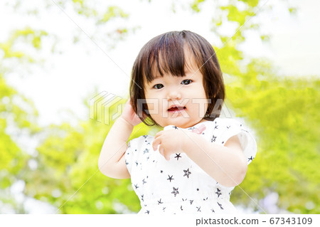 新鮮的綠樹為背景的微笑跳舞的小女孩 67343109