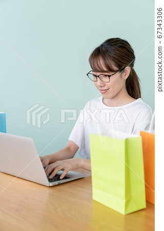 A young woman shopping online with a personal computer A young woman shopping online with a personal computer 67343306