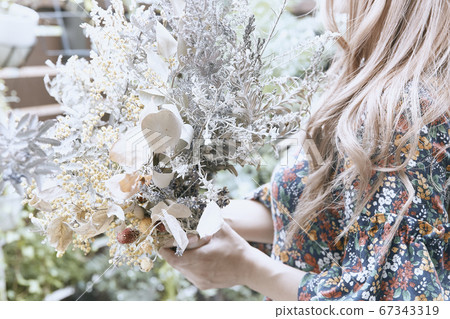 Photogenic photo of curly-haired woman and plant in dried flower and floral dress 67343319