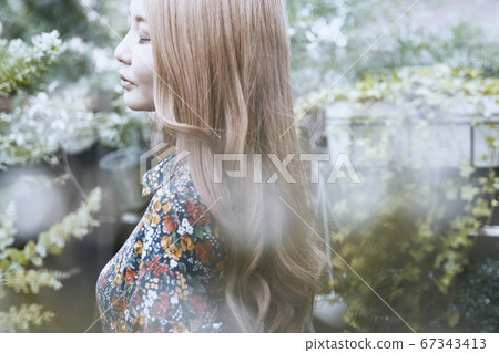 一名捲髮婦女的上鏡圖片有美麗的頭髮外形和植物背景的 一名捲髮婦女的上鏡圖片有美麗的頭髮外形和植物背景的 67343413